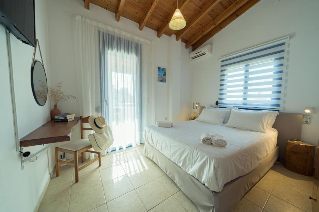 ParánimfoiSunset Home Crete的卧室配有白色的床、书桌和窗户。