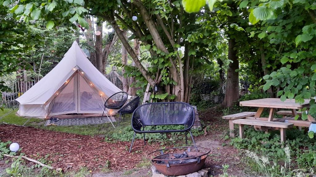 HerzeleGlamping Zonnebloem - Back-to-Nature的帐篷、椅子、桌子和长凳