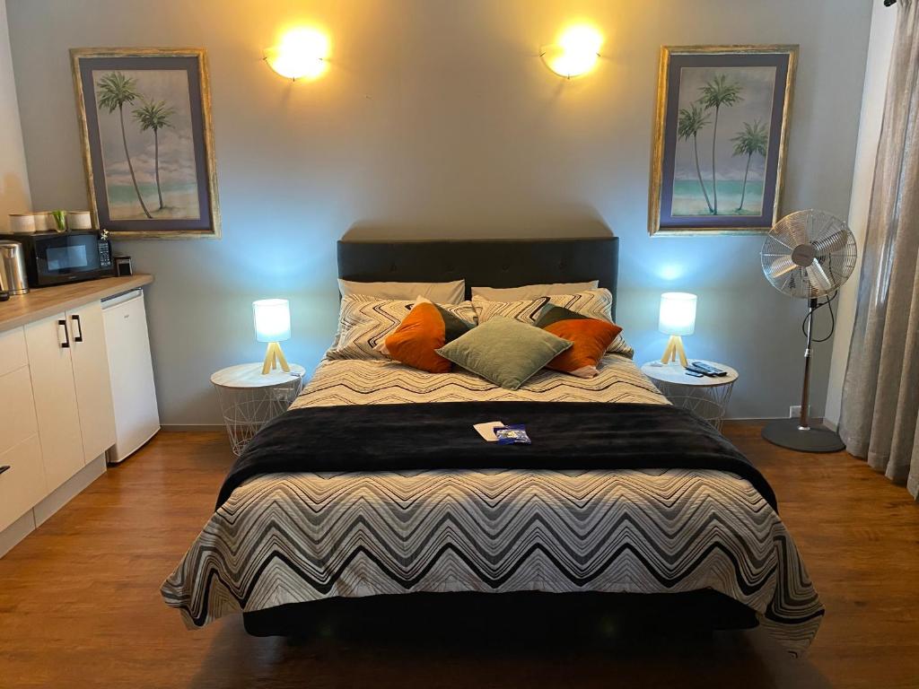 奥克兰Opanuku Out West的一间卧室配有一张带两盏灯的床和风扇。