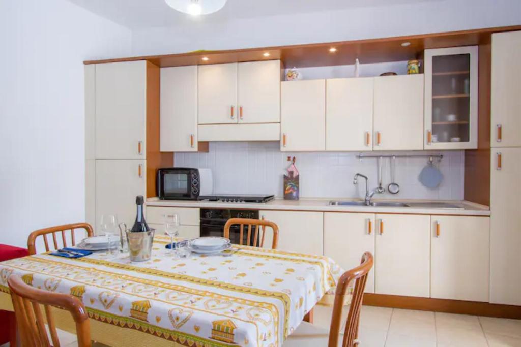奥特朗托Villa Lucetta的一间带桌子的厨房和一间带白色橱柜的厨房