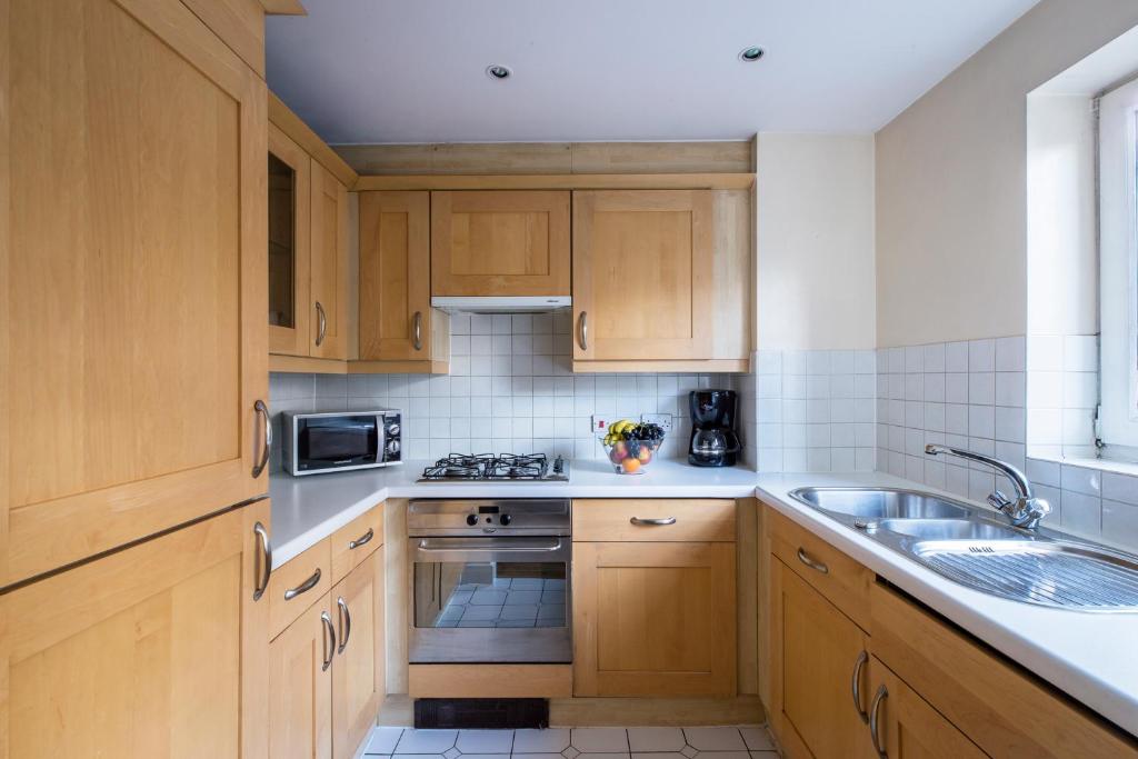 伦敦Royal London Apartments的带木质橱柜和水槽的厨房