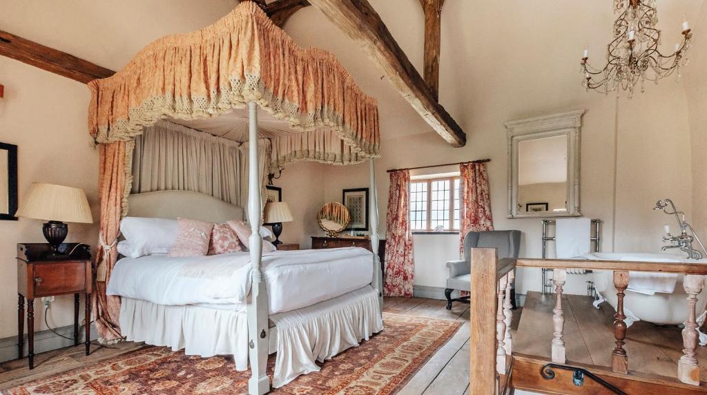 HalesLavish Tudor Estate & Gardens - Sleeps 25的一间卧室配有一张天蓬床和一个浴缸
