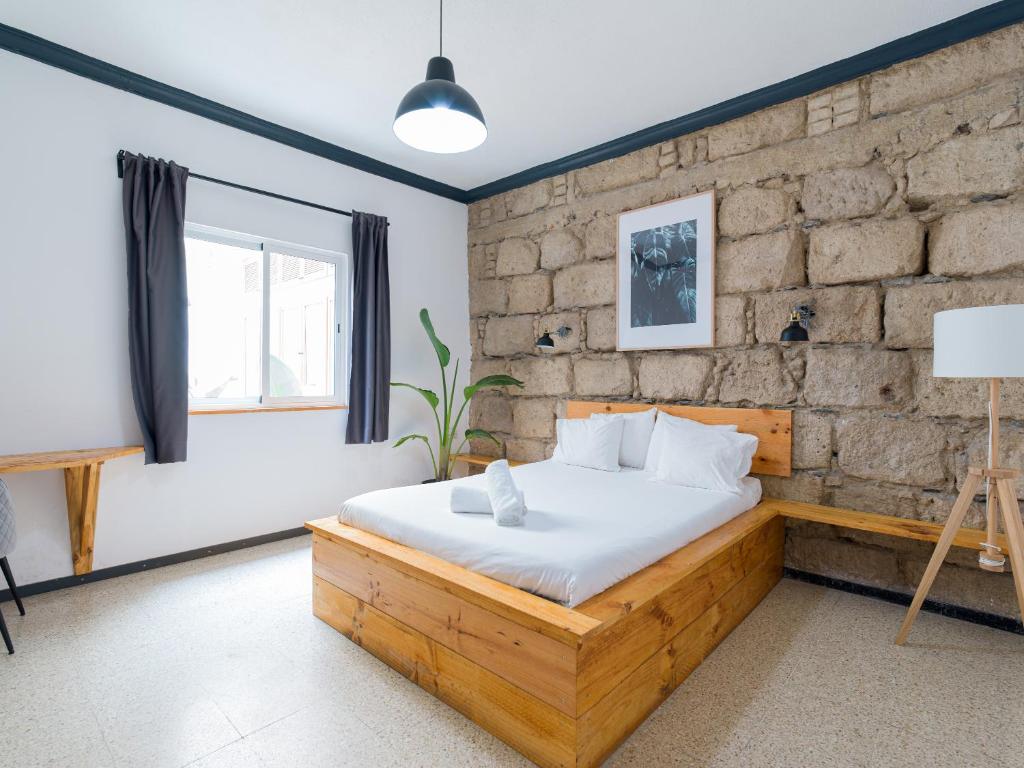 大加那利岛拉斯帕尔马斯Cathedral Apartment的一间卧室设有木床和砖墙
