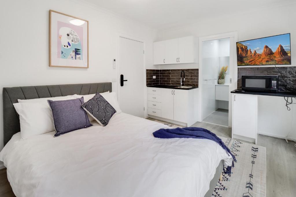 吉朗Highton Accommodation (Geelong)的一间白色卧室,配有床和厨房