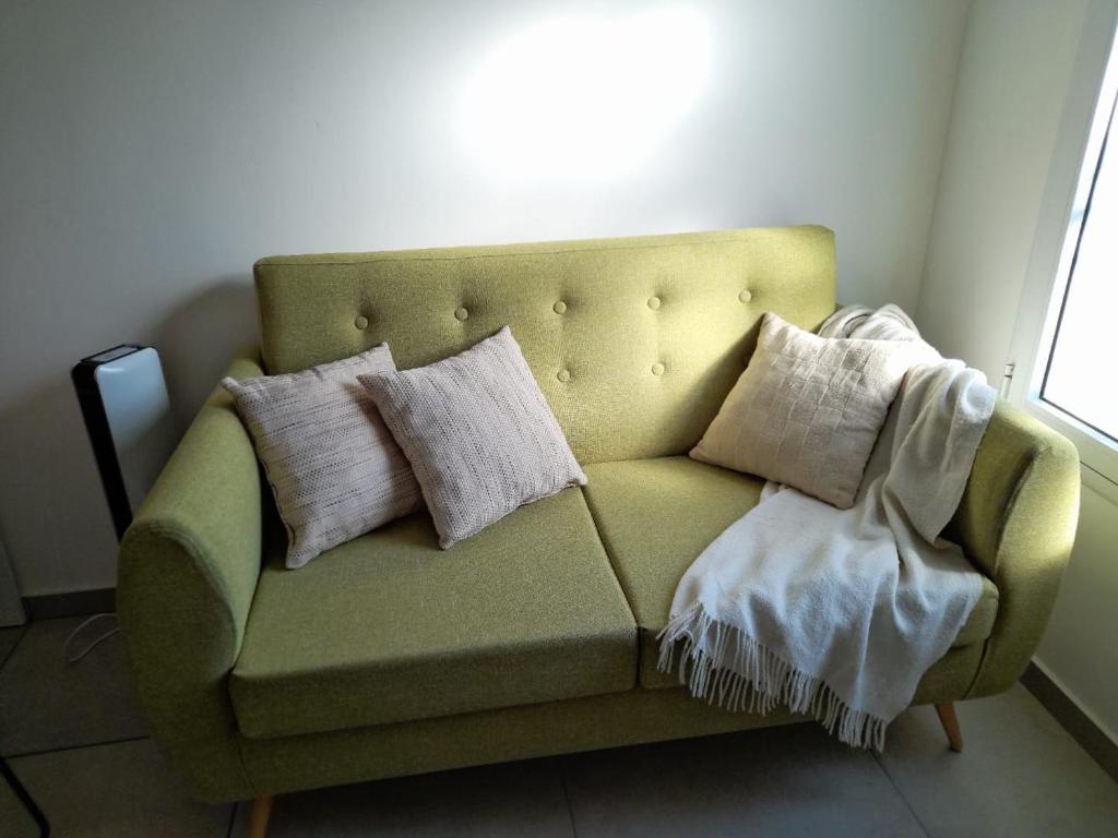 拉斐拉Departamento moderno y luminoso, en planta baja, con patio y excelente ubicación的客房内的绿色沙发上配有枕头