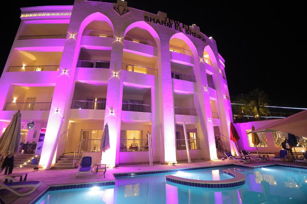 沙姆沙伊赫Jewel Sharm El Sheikh Hotel的一座建筑,在晚上前方有一个游泳池