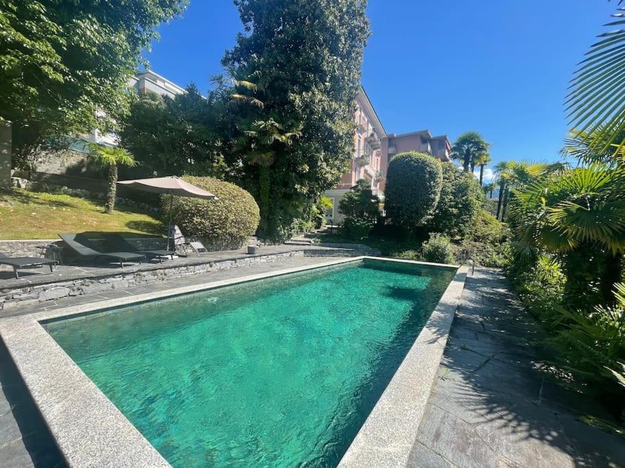 洛迦诺Villa Magnolia - Boutique Superior Rooms的庭院中带绿水的游泳池