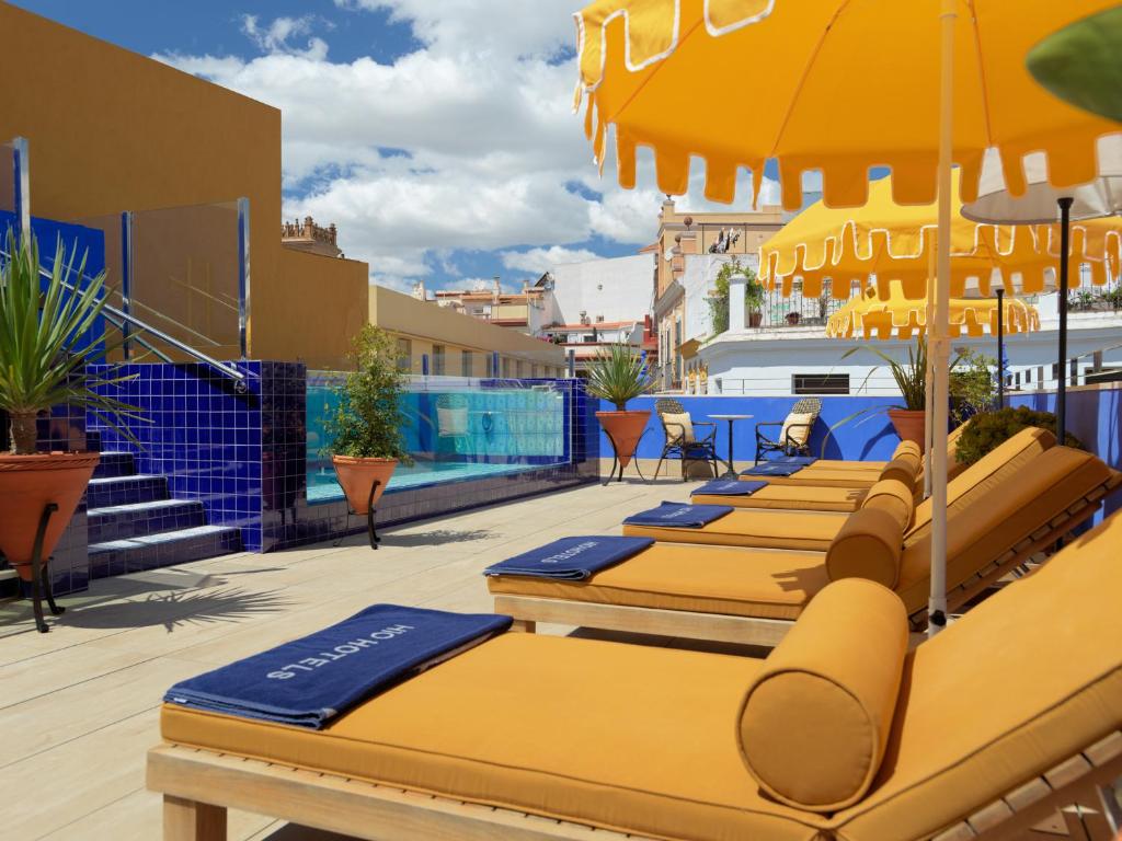 塞维利亚H10柯里基多精品酒店 的屋顶上一排带遮阳伞的长椅