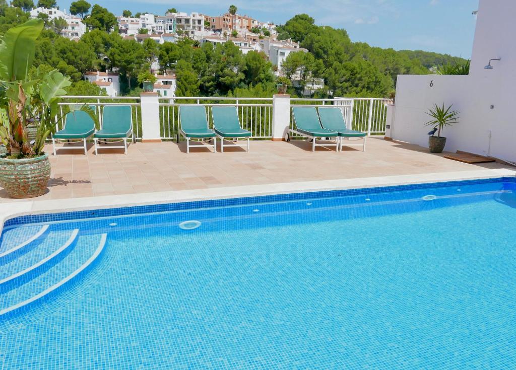 卡拉加尔达纳Es Cucó的一座带蓝色椅子的游泳池,位于大楼旁