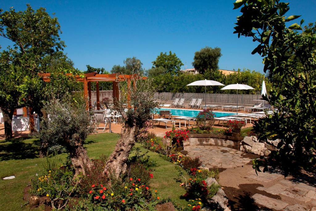 索伦托伊尔罗塞托酒店的花园设有游泳池、桌子和遮阳伞