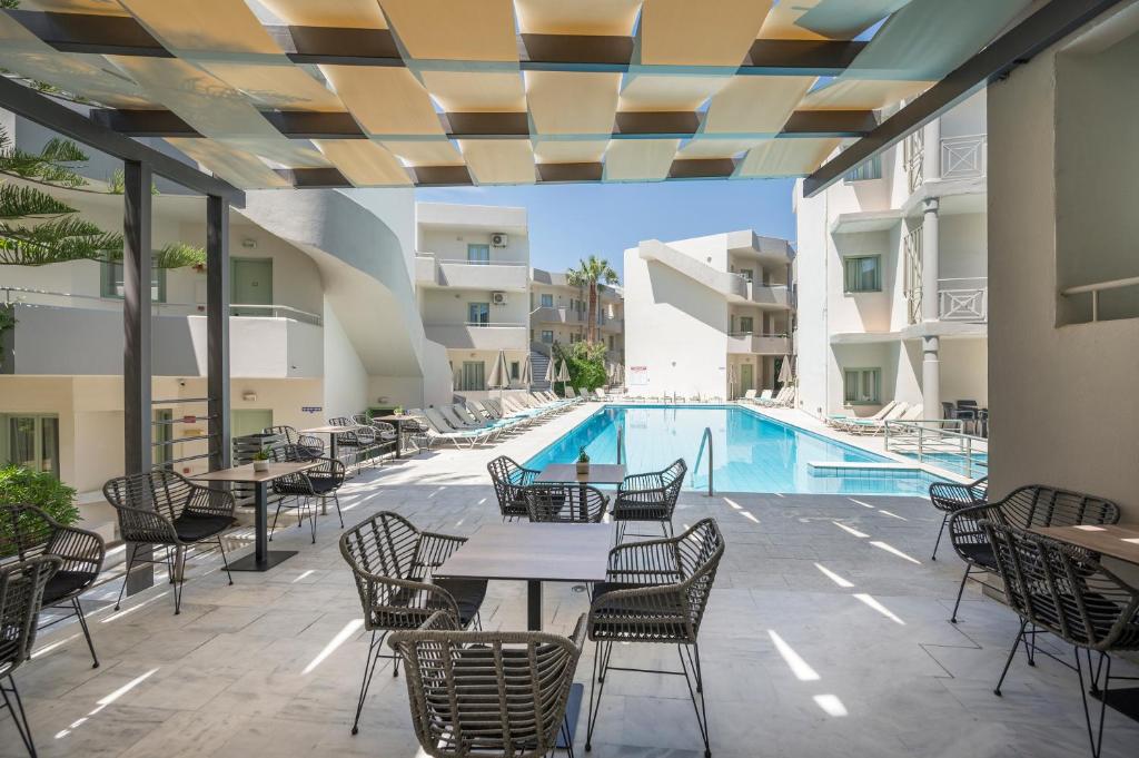 GeorgioupoliSummer Beach Hotel的一个带桌椅的户外庭院和一个游泳池