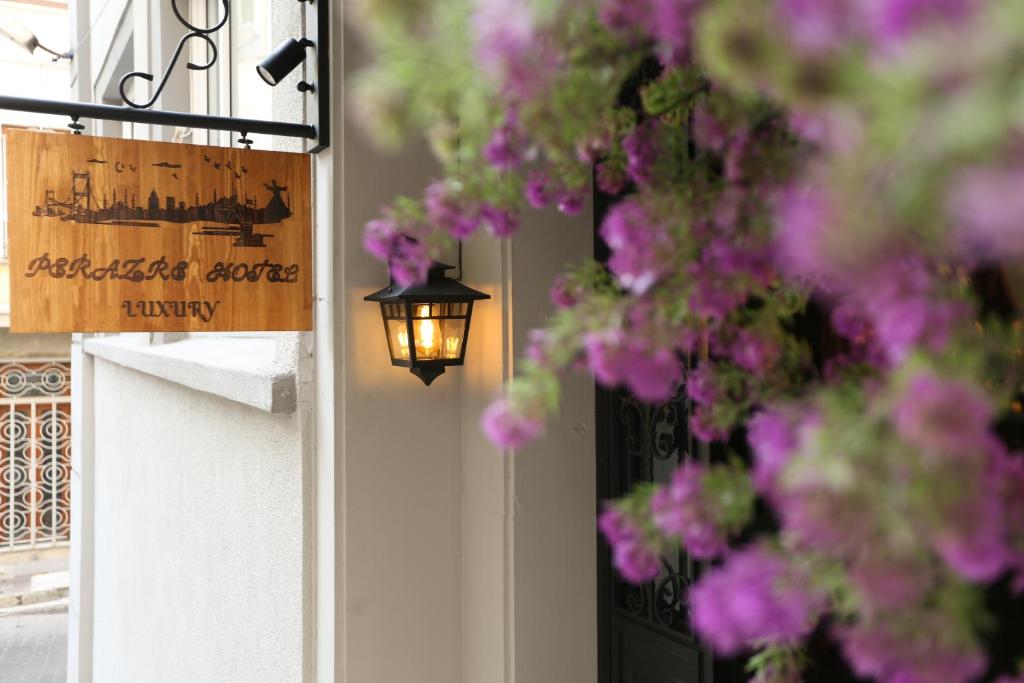 伊斯坦布尔Perazre Hotel的门上带有紫色花朵和灯的标志