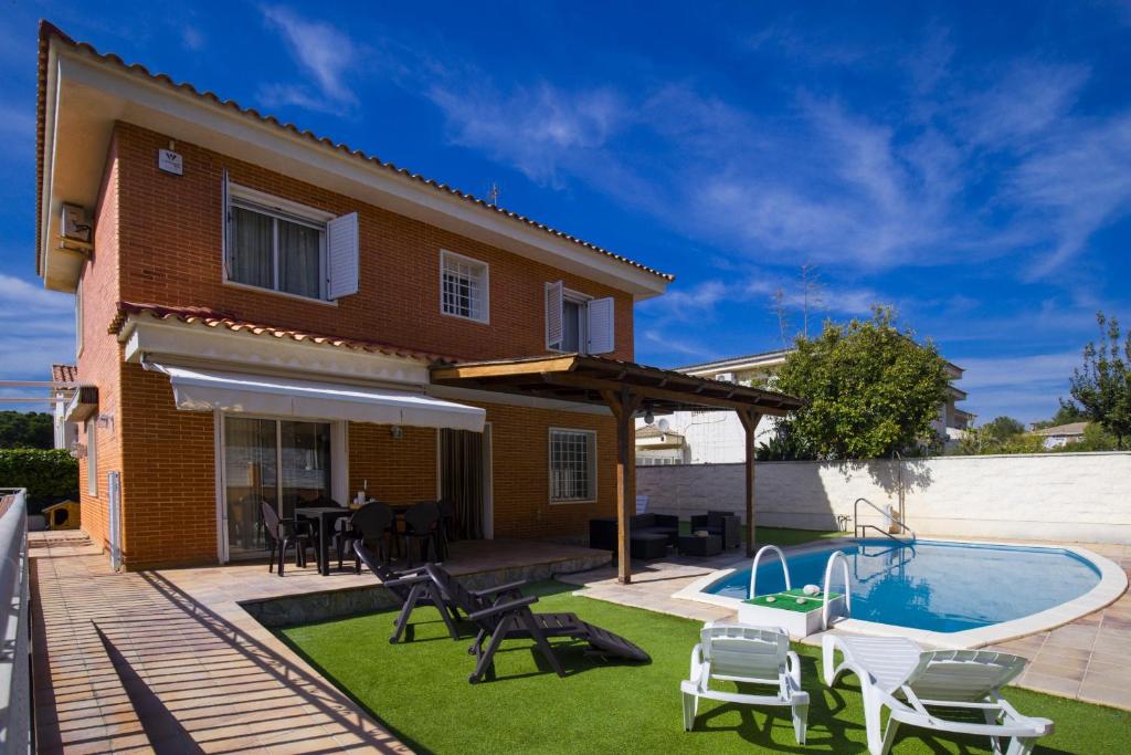萨洛Villa PLUMA Planet Costa Dorada - ONLY FAMILIES的一个带游泳池和房子的后院