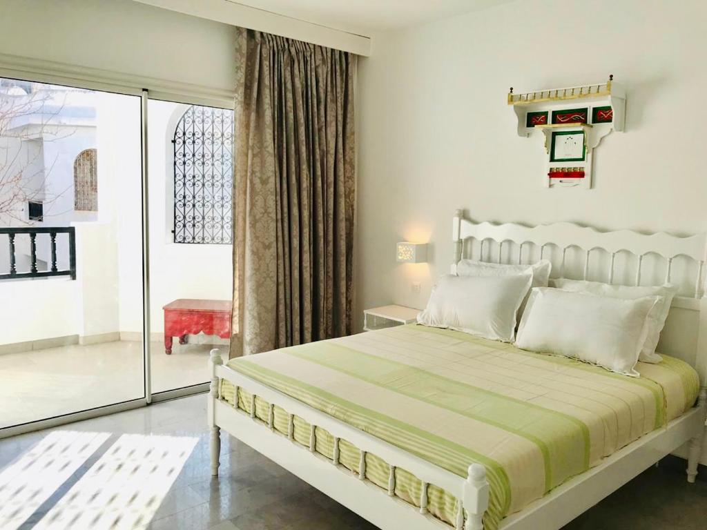 哈马马特Résidence Neffati的白色卧室设有床和滑动玻璃门