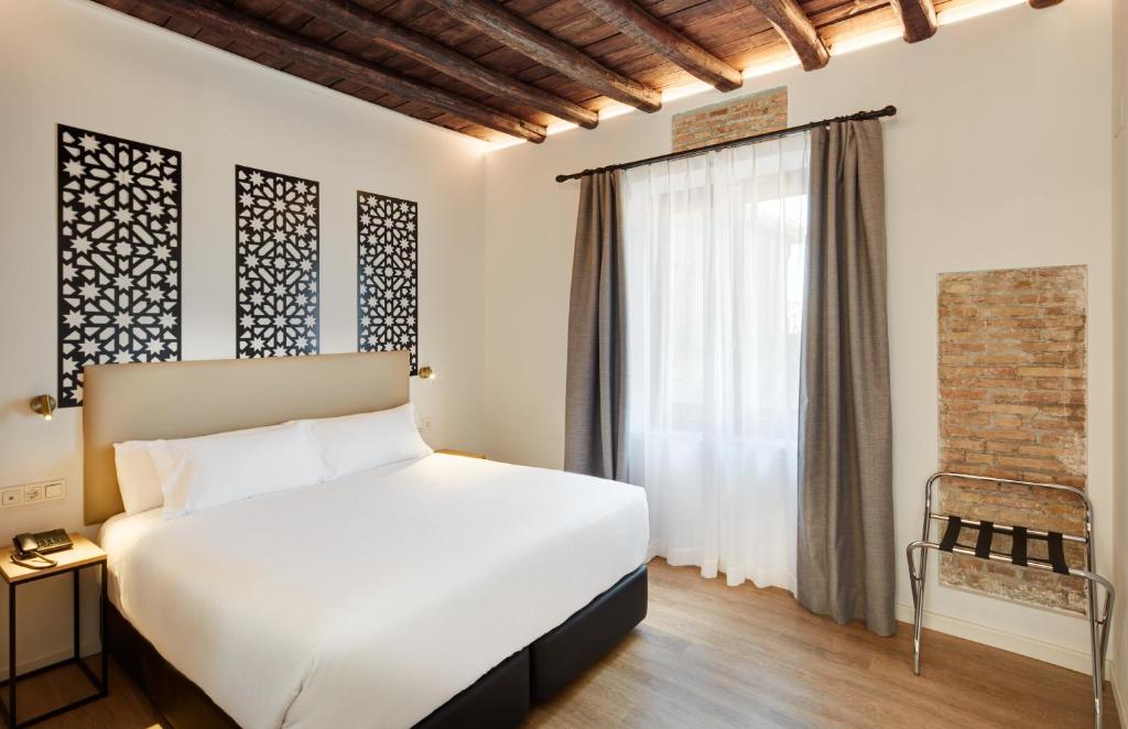 格拉纳达Sercotel Granada Suites的卧室配有白色的床和窗户。