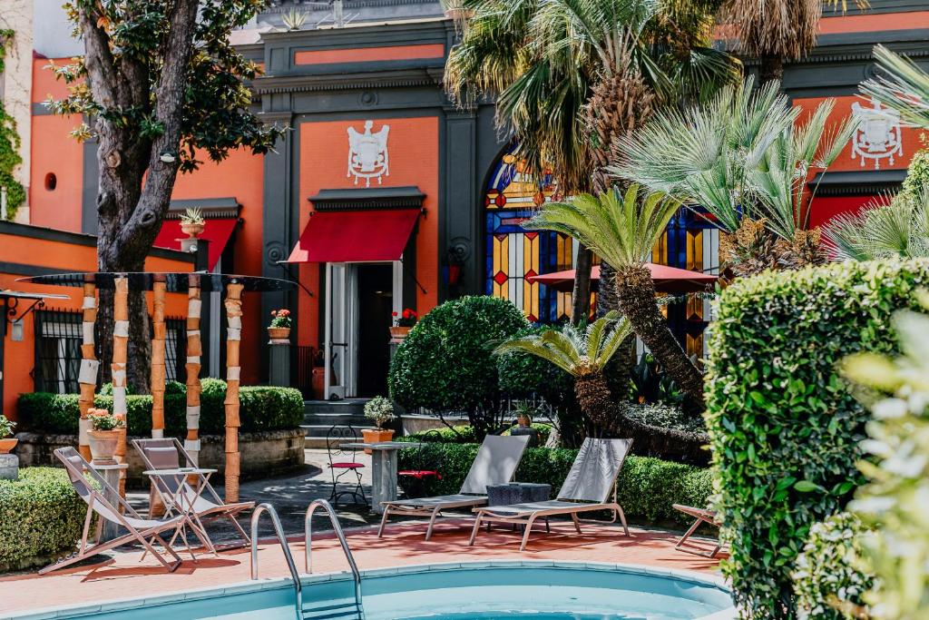 那不勒斯柯斯坦提诺波里104酒店的一座带椅子的庭院和一座位于大楼前的游泳池