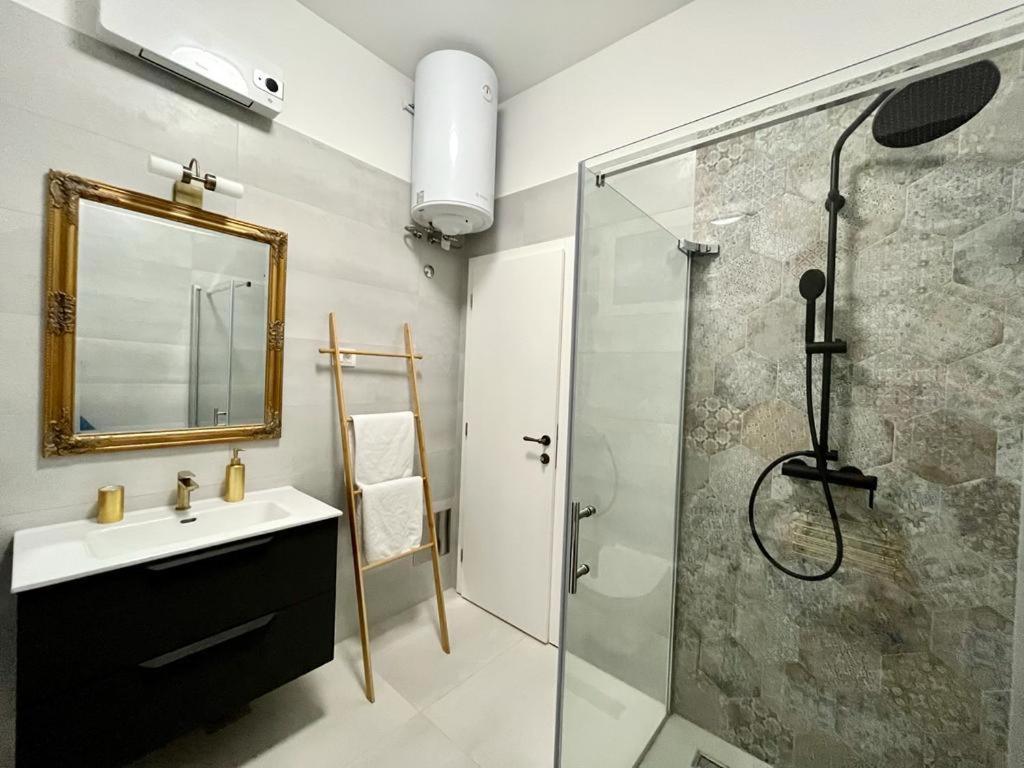 普拉Lux Apartmans的浴室配有盥洗盆和带镜子的淋浴