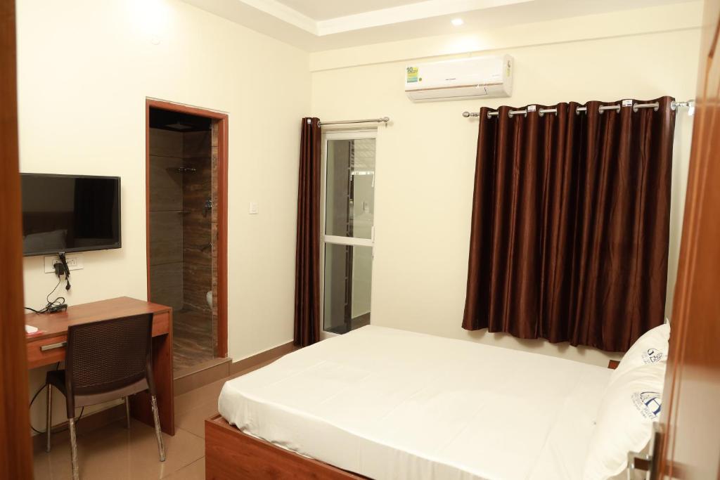 科钦Grace Apart Hotel @Kochi的一间卧室配有一张床、一张书桌和一台电视
