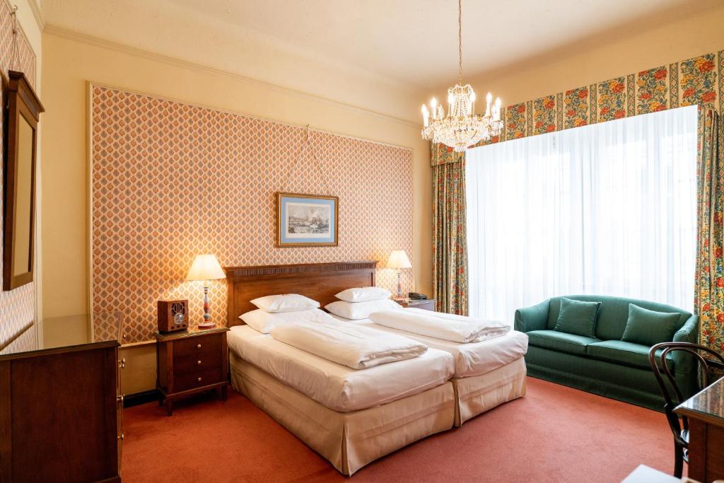 维也纳匈牙利国王饭店的一间卧室配有一张大床和一张绿色椅子