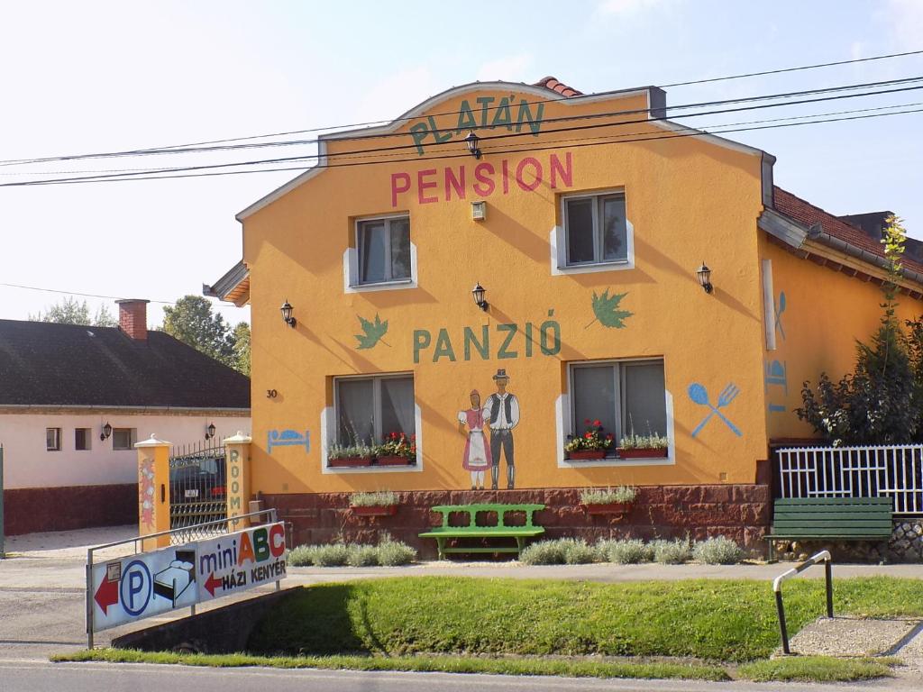 纽尔Platán Panzió的黄色的建筑,在建筑的一侧画着画