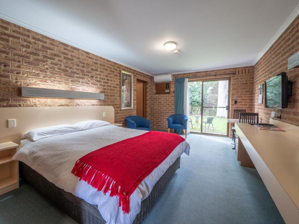 艾尔登Eildon Parkview Motor Inn Room 1的一间卧室配有一张带红色毯子的床