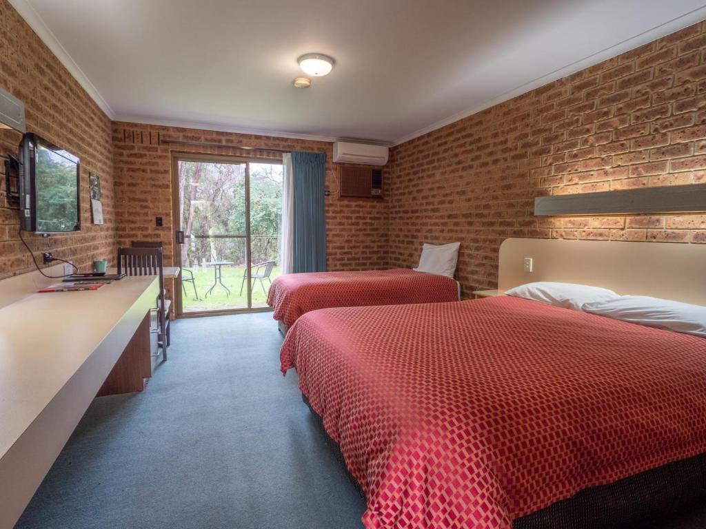 艾尔登Eildon Parkview Motor Inn Room 2的一间卧室设有两张床和砖墙