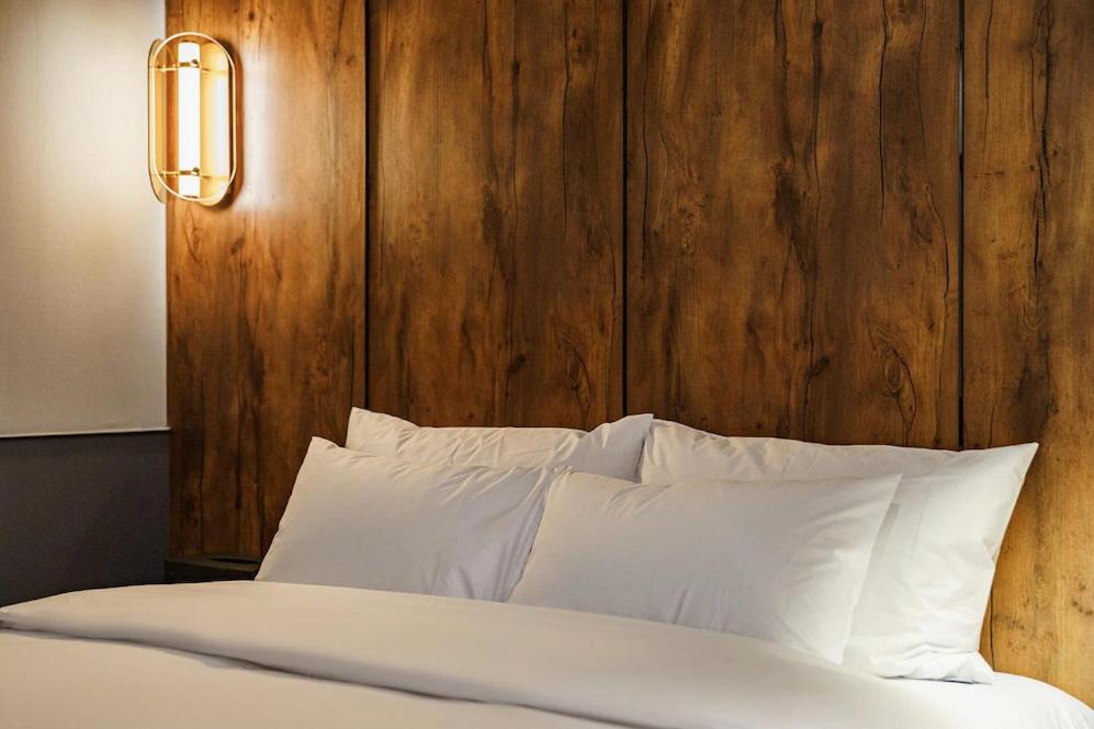 仁川市Brown-Dot Hotel Geomdan的一张带白色枕头和木制床头板的床