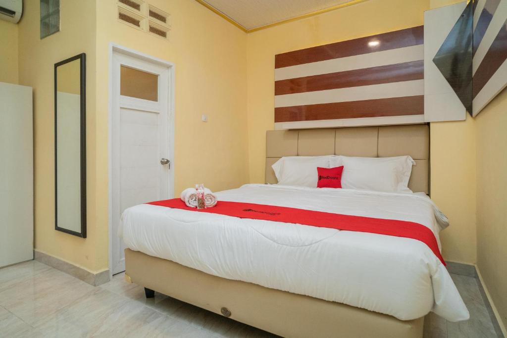 KandangsapiRedDoorz Plus Syariah near Pasar Turi的卧室配有带红色枕头的大型白色床