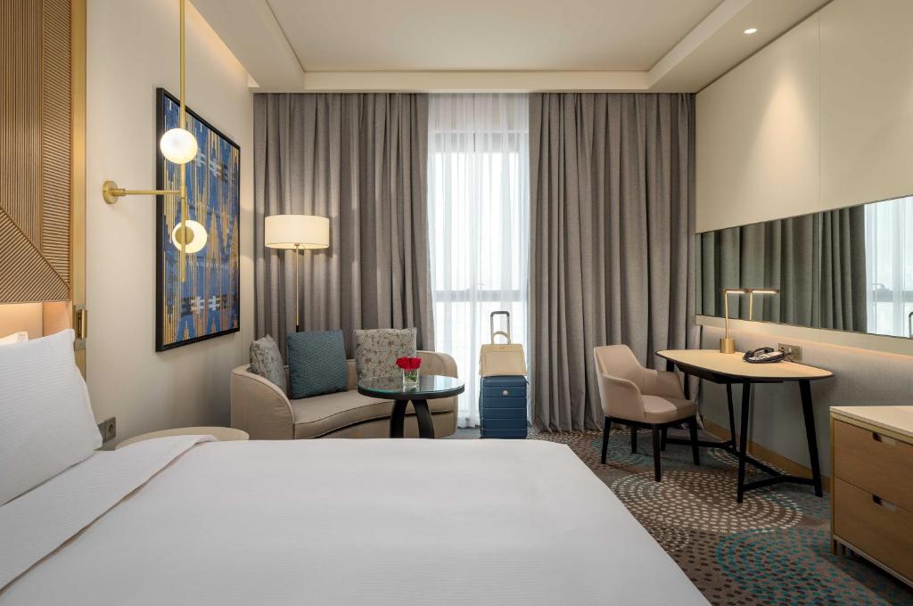苏莱曼尼亚Slemani Rotana的酒店客房带一张床、一张桌子和椅子