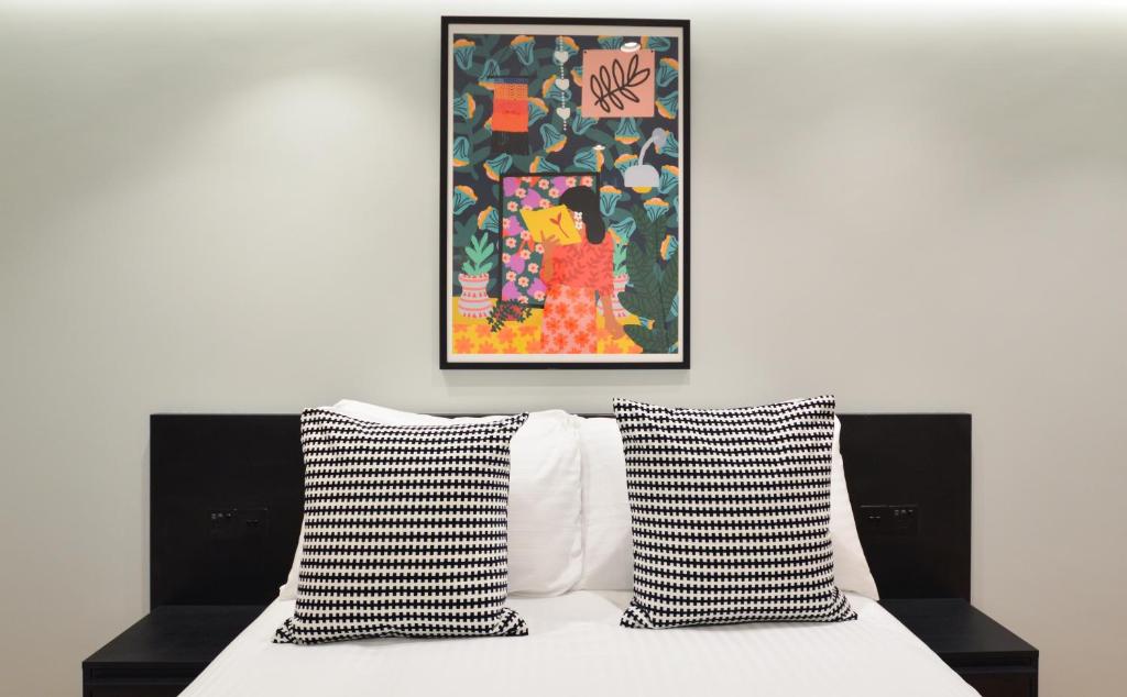 伦敦Earls Court East Serviced Apartments by StayPrime的一张带黑白枕头的床和绘画
