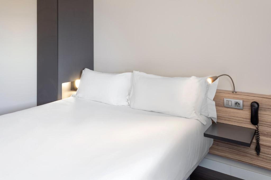 阿尔巴塞特B&B HOTEL Albacete的一张带白色枕头的床和电话