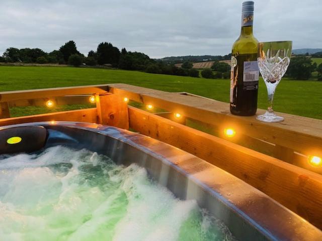 ThirklebyBurtree Country House and Retreats Tipi的一瓶葡萄酒和一杯热浴盆旁的玻璃