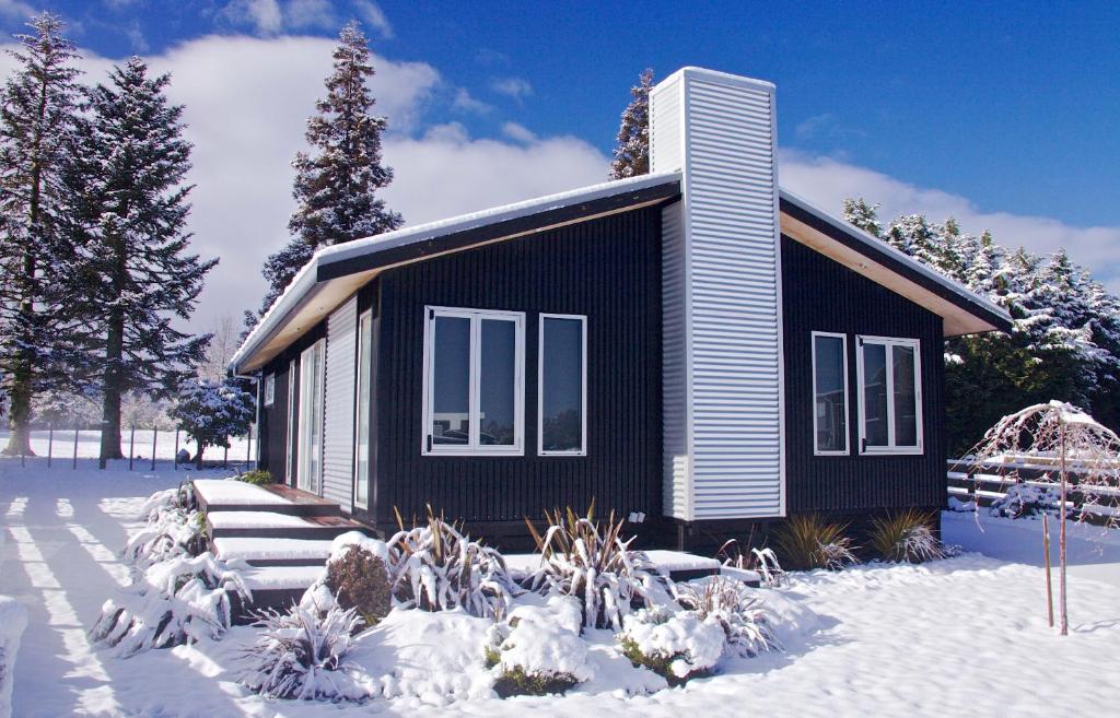 奥阿库尼Handbridge - Ohakune Holiday House的一间黑色的小房子,地面上有雪
