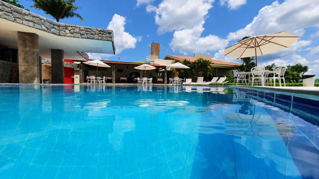 格拉瓦塔Hotel Três Palmeiras的一个带椅子和遮阳伞的大型游泳池