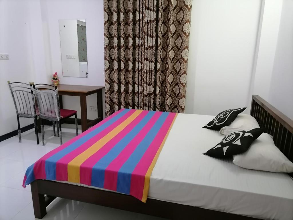阿鲁特伽马Nesh Villa的一间卧室配有一张带彩色条纹毯子的床