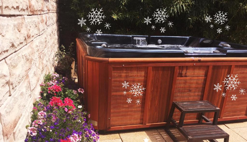 阿维尼翁Havre de paix Avignon avec Jacuzzi & Sauna的雪花花花花园里的木浴缸