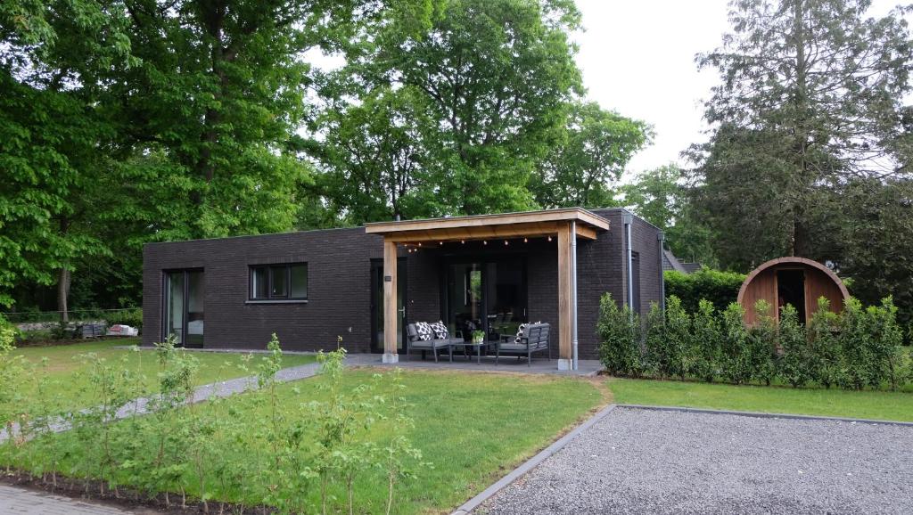 福尔特赫伊曾The White Oak - Luxe 4 persoons bungalow met prive sauna的一座带花园的庭院中的黑色房子