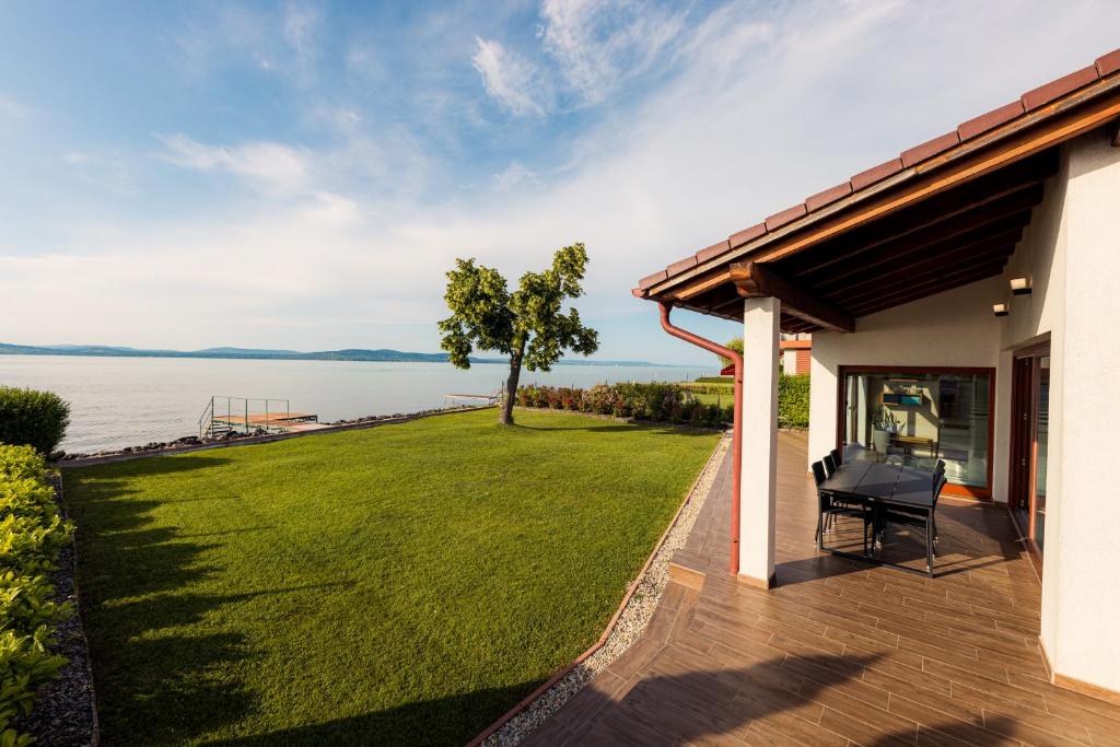 巴拉顿博格拉尔Balaton View Apartment的房屋设有1个带草坪和水的庭院