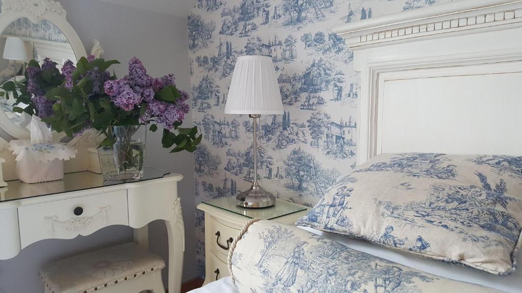 Graiguenamanagh布兰登美景屋住宿加早餐酒店的卧室配有蓝色和白色的壁纸、床和鲜花