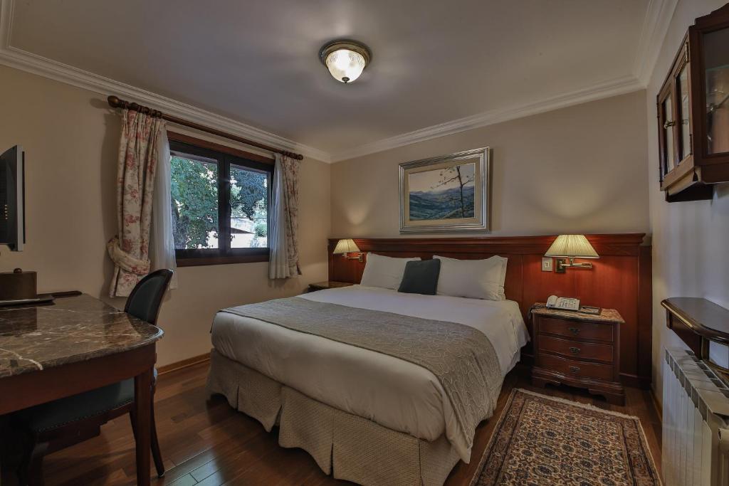 坎波斯杜若尔当Le Suisse Elegance Hotel的一间卧室配有一张床、一张书桌和一个窗户。
