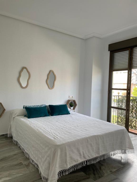 韦尔瓦Apartamento turístico La Joya的白色卧室配有一张带蓝色枕头的大床