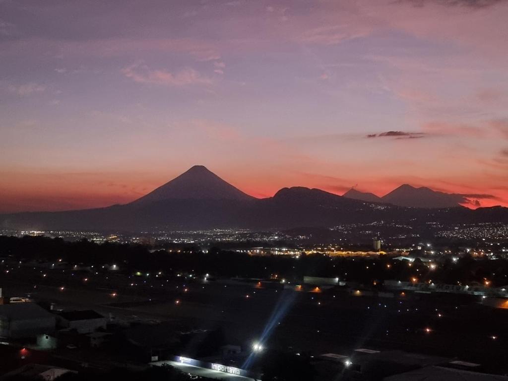 危地马拉Amazing Volcano Views in front of airport的日落时分享有城市和山脉的景致