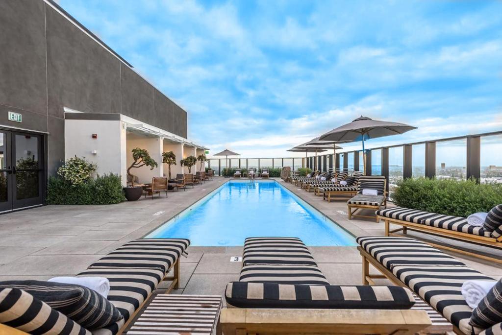 洛杉矶Sky-Rise Apartments的大楼内带躺椅和遮阳伞的游泳池