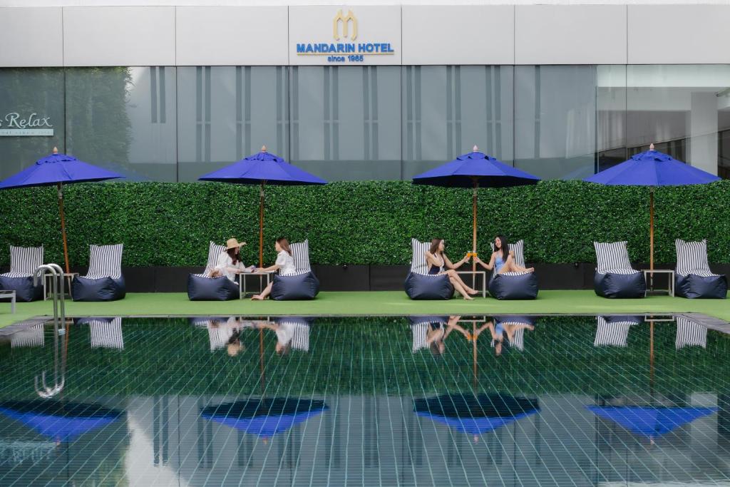 曼谷Mandarin Hotel Managed by Centre Point的一群人坐在游泳池旁边的沙发上