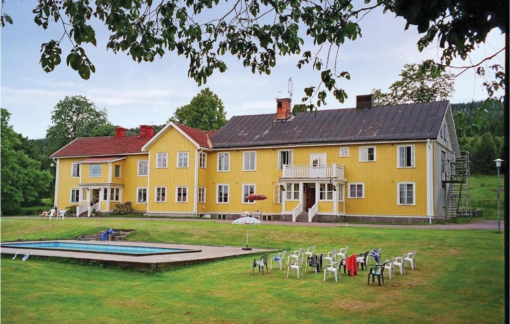 GräsmarkAwesome Home In Grsmark With Sauna的一座黄色的大房子,前面设有一个游泳池