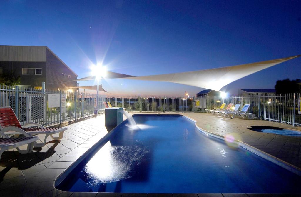 威廉斯敦奎斯特北威廉斯敦酒店的一座带椅子的夜间游泳池和一座建筑