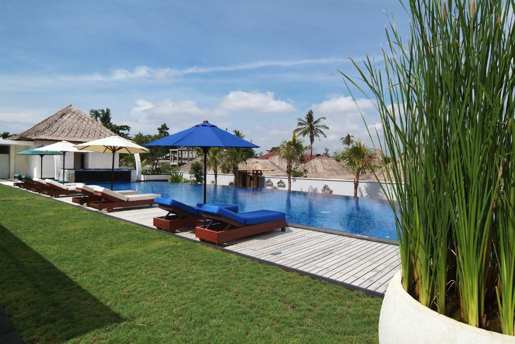沙努尔Villa Mahapala的毗邻度假酒店的带椅子和遮阳伞的游泳池