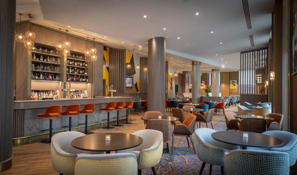曼彻斯特Maldron Hotel Manchester City Centre的一间带桌椅的餐厅和一间酒吧