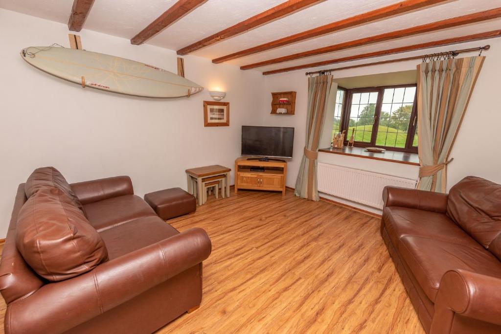 伍拉科姆Point Cottage的客厅配有沙发和冲浪板。