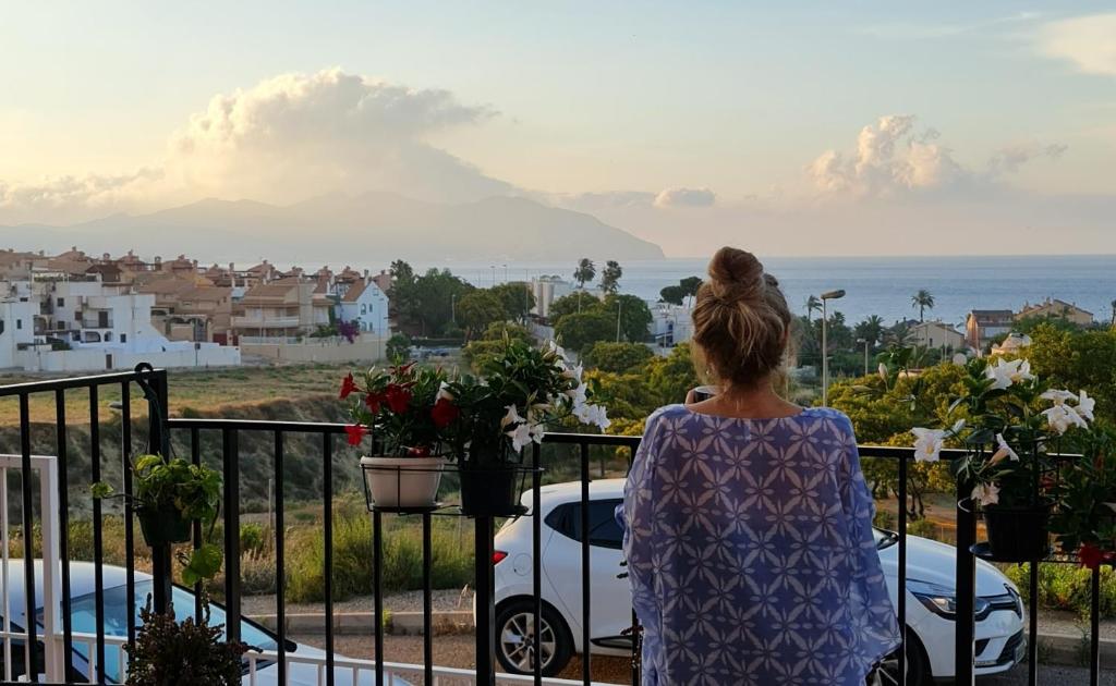 马萨龙港SunRise Den, a pie de playa, vista al mar y piscina的站在一个眺望海洋的阳台上的女人